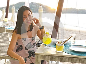 Beautiful woman holding a fruit cocktail on a tropical beach at sunset