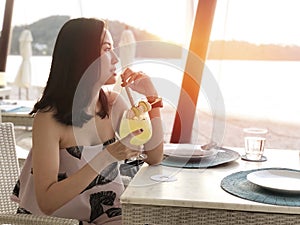 Beautiful woman holding a fruit cocktail on a tropical beach at sunset