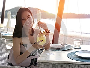 Beautiful woman holding a fruit cocktail on a tropical beach at sunset