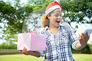 Beautiful woman holding gift boxs with wearing santy hat at the garden.