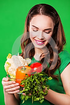 Beautiful woman holding a grocery bag full of fresh and healthy food. on green background
