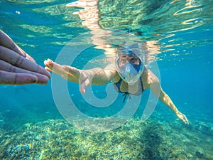 Beautiful woman holding hand snorkeling under water
