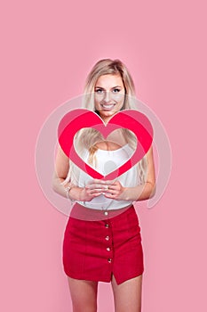 Beautiful woman holding red heart in hand. Cute girl expressing tender love feelings