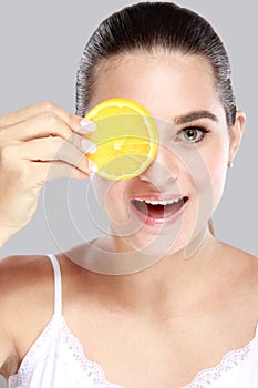 A beautiful woman holding a slice of fresh lemon