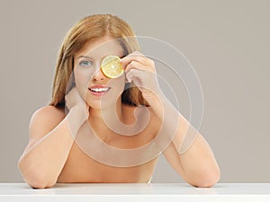 Beautiful woman holding slice of lemon eye