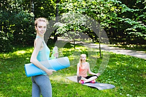 Beautiful woman holding a yoga mat and water bottle