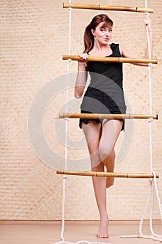 Beautiful woman holds on bamboo rope ladder