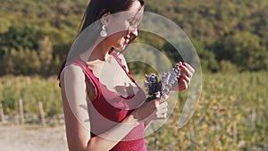 Beautiful woman holds bouquet of wild flowers and sniffs them, slow motion