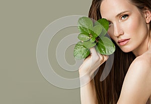 A beautiful woman holds green leaves in her hands. Cleanliness and care