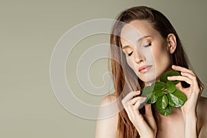 Beautiful woman holds a green leaves in her hands. Cleanliness and care