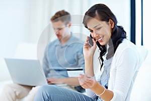 Beautiful woman at home paying bills with credit card. Beautiful woman shopping over phone with credit card while man