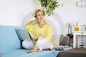Beautiful woman at home in smart work activity sitting on the couch and working on a laptop compuer - modern people and technology