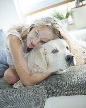 Beautiful woman hugging dog on sofa