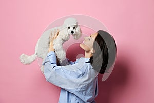 Beautiful woman hugging her lovely white poodle dog puppy on pink