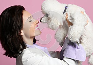 Beautiful woman hugging her lovely white poodle dog puppy on pink happy smiling