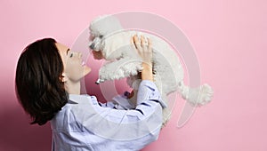 Beautiful woman hugging her lovely white poodle dog puppy on pink happy smiling