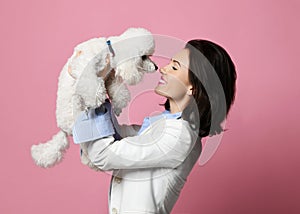 Beautiful woman hugging her lovely white poodle dog puppy on pink happy smiling