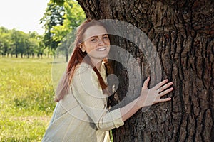 Beautiful woman hugging tree trunk