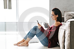 Beautiful woman indoors in home on sofa using mobile phone