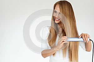 Beautiful Woman Ironing Long Straight Hair With Straightener photo
