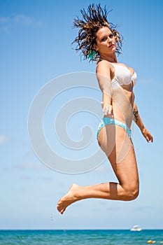 Beautiful woman is jumping against blue sky