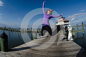 Beautiful woman jumps on a dock alongside the Choptank River Lighthouse in Maryland