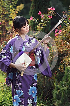 Beautiful woman with kimono playing shamisen