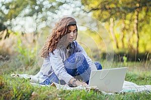 Beautiful woman with laptop on the grass