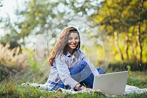 Beautiful woman with laptop on the grass