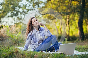 Beautiful woman with laptop on the grass