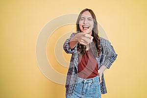 beautiful woman laughing with hand gesture pointing at camera while standing with copyspace