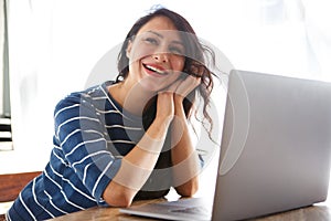 Beautiful woman laughing and sitting at desk with laptop