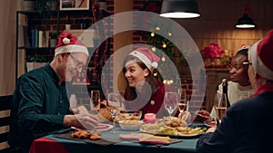 Beautiful woman laughing and talking with senior father-in-law while enjoying Christmas dinner at home.