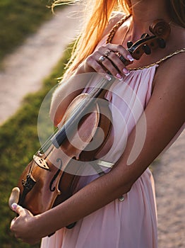 Beautiful woman learning to play violin in nature background