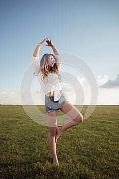 Beautiful woman with legs and denim shorts on grass, shoe less