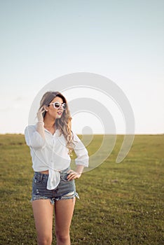 Beautiful woman with legs and denim shorts on grass, shoe less