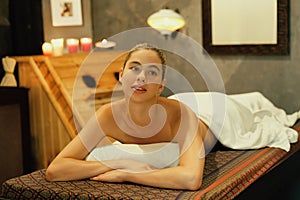 Beautiful woman lies on spa bed in front of wooden sauna cabinet. Tranquility.
