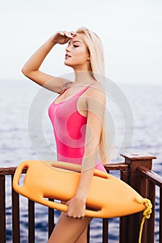 Beautiful woman lifeguard with rescue board watching on the beach at safity on the water. Lifeguard job on summer vocation.