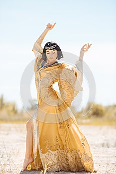 Beautiful woman like Egyptian Queen Cleopatra on in desert outdoor.
