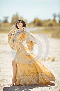 Beautiful woman like Egyptian Queen Cleopatra on in desert outdoor.