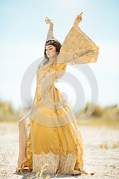 Beautiful woman like Egyptian Queen Cleopatra on in desert outdoor.