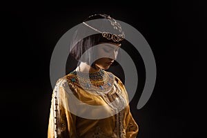 Beautiful woman like Egyptian Queen Cleopatra with sad face on black background