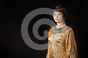 Beautiful woman like Egyptian Queen Cleopatra with serius face against black background