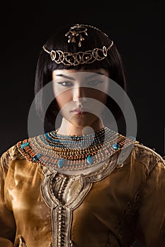 Beautiful woman like Egyptian Queen Cleopatra with serius face on black background