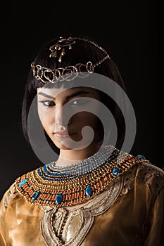 Beautiful woman like Egyptian Queen Cleopatra with serius face on black background