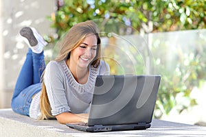 Beautiful woman on line browsing social media with a laptop outdoor photo