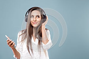 Beautiful woman listening to music using wireless headphones in studio isolated over blue background