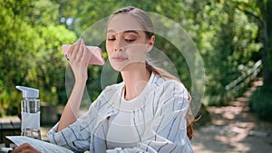 Beautiful woman listening voice message relaxing at park with notepad close up.