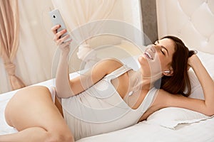 Beautiful Woman Listens a Music lying on the bed