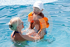 Beautiful woman and little boy bathes in pool